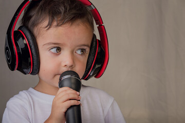Little boy singing music with microphone and headphones
