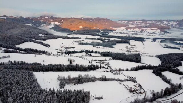 A slowly moving 4K drone flight during sunset over a beautiful winter landscape with moving clouds. Location is the Schoecklland near Graz in Austria
