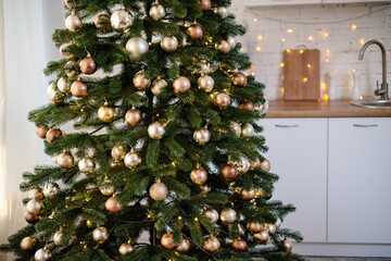 The tree is decorated with colorful toys and a garland. Close-up photo in warm colors. Christmas and New Year atmosphere