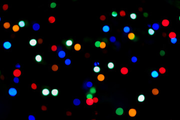 Multicolored bokeh of Christmas garlands on a Christmas tree at night on Christmas Eve and New Years. Bright flashes of colored lights, bokeh texture. Festive colorful background Disco lights at party