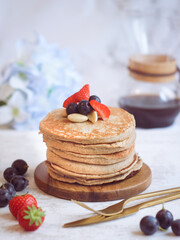 A healthy rolled oat banana on a wooden plate with fresh strawberries and red grapes with a pot of coffee in the background. A high fiber and high protein food for diet people 