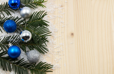 The concept of a holiday postcard on a wooden base with a blank space for writing a message. Blue and gray decorative, fir branches and snow.