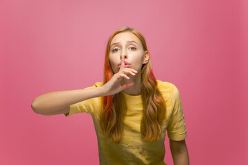 Worried young teen girl showing silence gesture, ask to keep secret on pink studio background. Privacy concept
