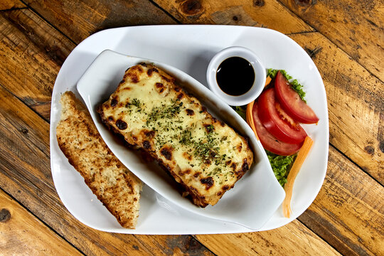 Lasagna On White Plate With Bread And Salad