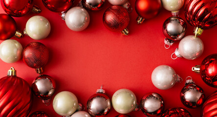 Banner made of Christmas colorful balls decoration and tree branches on red background. New Year greeting card. Minimal style. Flat lay, top view, copy space.