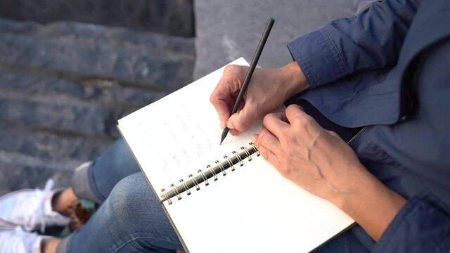 Hand writing in diary, unrecognizable girl writing a poetry by the sea