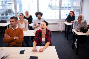 Multi ethnic students listening to a lecturer in a classroom. Smart young people study at a college.