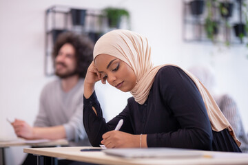 Multi ethnic students listening to a lecturer in a classroom. Smart young people taking a test at a...