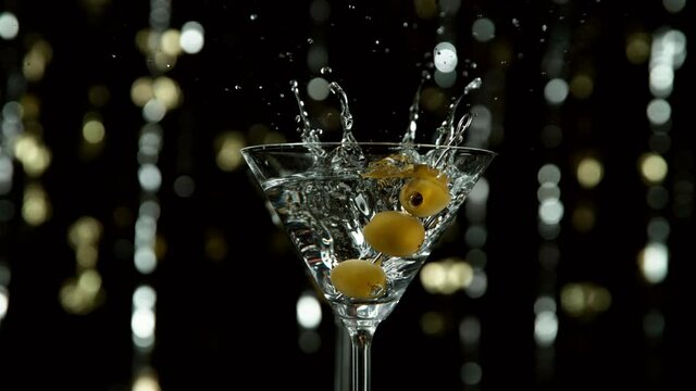 Super slow motion of falling olives into cocktail drink, camera movement. Filmed on high speed cinema camera, 1000 fps.