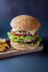 delicious large double burgeon with vegetables cutlet veal meat with lettuce and cheese on a wooden board .Hamburger with fries