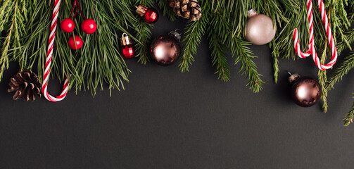 Christmas Banner made of decoration and xmas tree branches on black background. New Year greeting card. lay, top view, copy space.