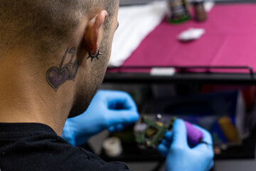 portrait of a professional tattooist preparing the tattoo gun or tattoo machine before performing a tattoo.