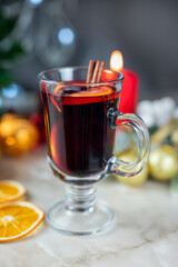 delicious hot spicy red mulled wine with orange and cinnamon spices near the Christmas tree with decorations and bokeh garlands