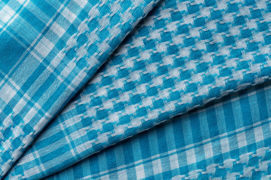 Folded keffiyeh of azure white colors background. Draped cotton shemagh texture. Arab desert scarf hirbawi. Full frame blue kefia pattern. Middle East head scarf kufiya.