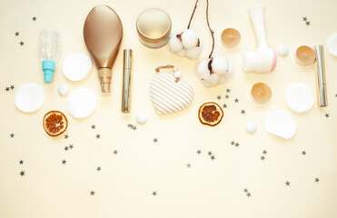 Accessories for spa treatments, body and face care and makeup. Lotions, creams, cotton pads, cotton flowers, mascara, a wash brush on a beige background. Flat lay.