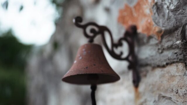 Old iron rusty bell on a stone wall