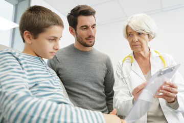 female-doctor with clipboard talks dad and little boy