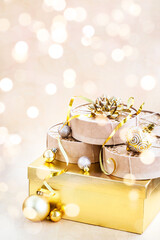 Christmas or New year round kraft gift boxes, gold holiday balls on a bokeh background of twinkling party lights of garland