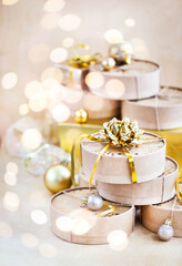 Fototapeta na wymiar Christmas or New year round kraft gift boxes, gold holiday balls on a bokeh background of twinkling party lights of garland