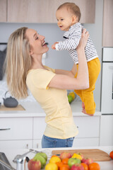 beautiful young mother holding her cute baby at kitchen