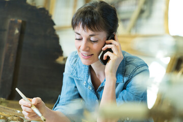 woman talking on mobile phone while renovating picture frame