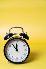 black alarm clock on a yellow background, the concept of time optimization. High quality photo