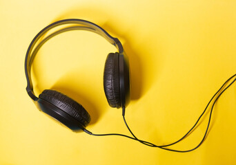 black headphones lying on a yellow isolated background