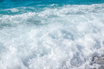 Naklejka na ściany i meble Shining waves splash close-up with white foam droplet hitting pebble beach. Clear blue water on Island in Greece. Summer travel to Ionian Sea
