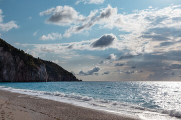 Clouds above Mylos beach shore on sunny coast with high cliffs and blue seascape. Lefkada island in Greece. Summer travel to Ionian Sea