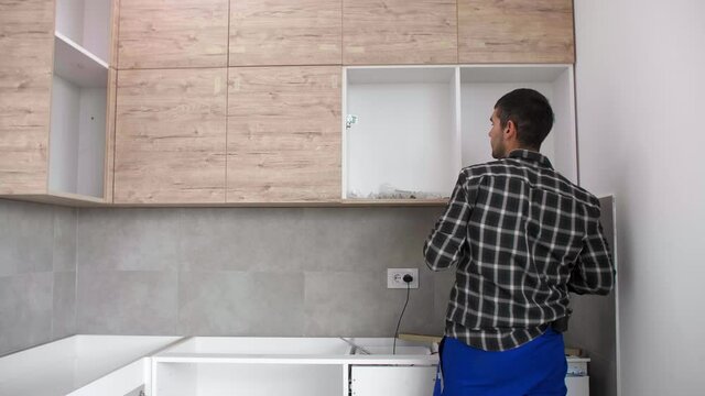 The carpenter sets the door of the kitchen shelves