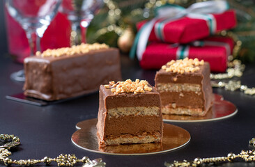 Fototapeta na wymiar Sliced mousse desserts with hazelnut praline, milk chocolate and covered gourmet chocolate-nut glaze on new year background, Close-up