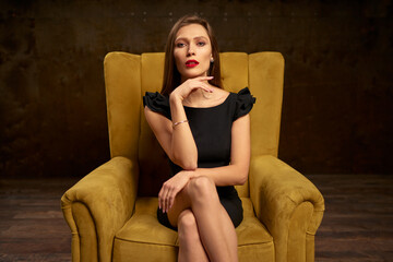 Portrait of a stunning fashionable model sitting in a chair. Business, elegant businesswoman.