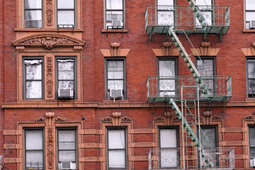 Old New York apartment building with fancy terra cotta detailing around windows and external fire...