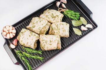 Fresh marinated BBQ chicken.Raw marinated chicken thigh in a light herb sauce on a grill pan, on a light background.Raw meat.