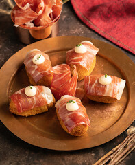 Close-up of Iberian ham croquettes and thin slices on top with kimchi and cilantro mayonnaise.