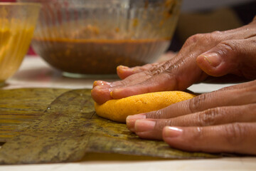 Traditional Venezuelan cuisine for the December festivities, hands preparing Hallacas. Typical dish of ancient traditions where a mixture of ingredients are wrapped in banana leaves