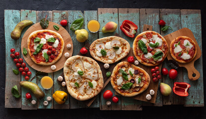 Pizza party at home with pears, mushrooms, tomatoes, basil, greens and vegetables on cutting boards