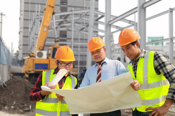 team of construction workers discussing project with executive supervisor on site with blueprints