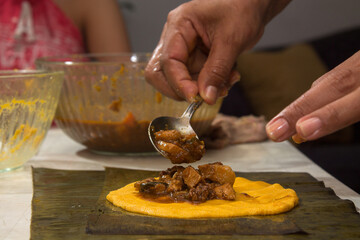 Traditional Venezuelan cuisine for the December festivities, hands preparing Hallacas. Typical dish of ancient traditions where a mixture of ingredients are wrapped in banana leaves