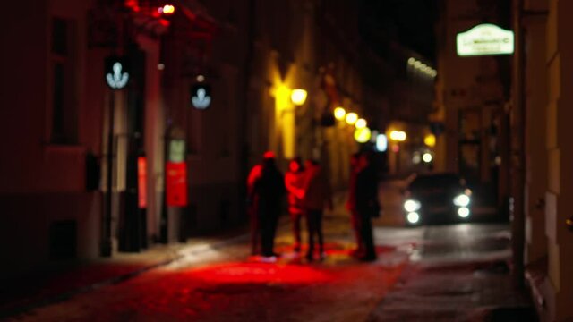 Group of tourists chatting outside a bar with red lights at entrance