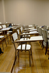 desks in a classroom with notebooks and pens, with no people occupying the seats.