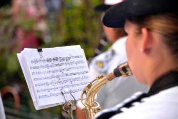 woman musician and member of a military band plays a wind instrument and reads sheet music