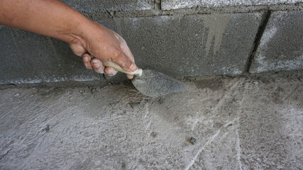 Hand holding a mortar trowel for the construction of the garden accommodation.