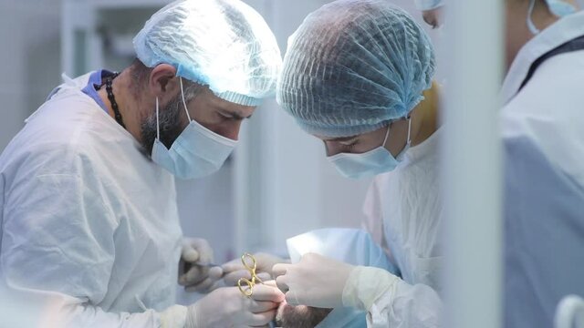 Surgeon and nurse during a dental operation.Anesthetized patient in the operating room.Installation of dental implants or tooth extraction in the clinic. General anesthesia during orthodontic surgery.