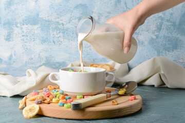 Woman adding milk to crunchy corn flakes rings in pot