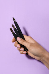 Female hand with manicure instruments on purple background