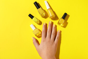 Female hand and nail polishes on yellow background