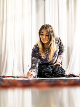 Young female Indigenous artist painting indoors