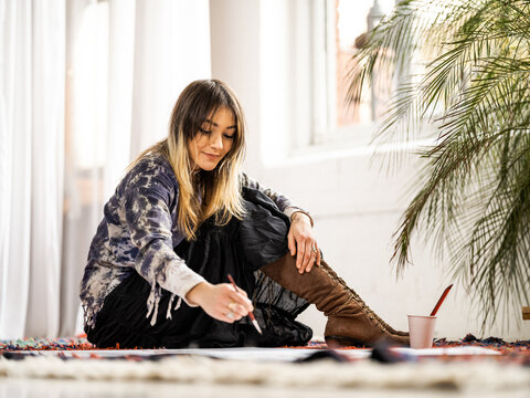 Young female Indigenous artist painting indoors