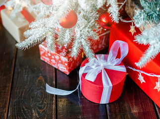 Christmas gift box with christmas balls on red background. Kraft paper box with red ribbon. High quality photo